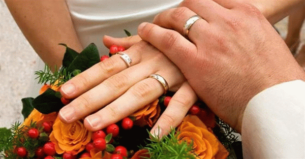 Руки с обручальными кольцами и букет цветов